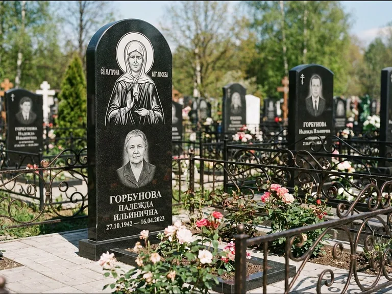 Памятник с гравировкой иконы: стела с арочным верхом и киотом под образ — гравировка образа Матроны Московской, гранитный цоколь с тёмной плиткой, работа «Ковалёв» в Новосибирске