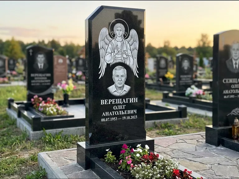 Памятник с гравировкой иконы: стела с резным навершием и нимбом в золоте — гравировка образа Спасителя, высокие разросшиеся туи полукругом, работа «Мельникова» в Новосибирске