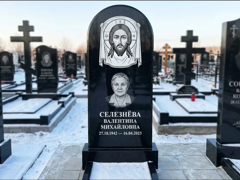 Памятник с гравировкой иконы: небольшая скромная одиночная стела с именной иконой — золочёный нимб на образе, аккуратный участок с газоном, работа «Ковалёв» в Новосибирске