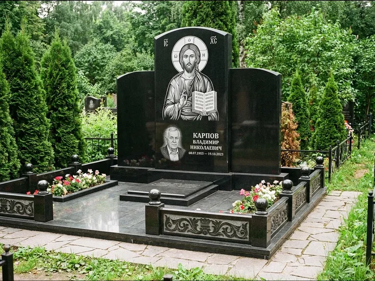 Памятник с гравировкой иконы: широкая панорамная стела с золочёным нимбом — гравировка образа Матроны Московской, цветник с белыми хризантемами, работа «Мельникова» в Новосибирске