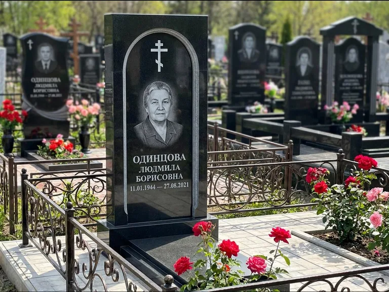 Памятник из чёрного гранита — скромная невысокая стела с крестом с терновым венцом, работа «Лаврентьева» в Новосибирске