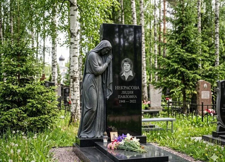 Гранитная фигура скорбящего мужчины у чёрной стелы в Новосибирске